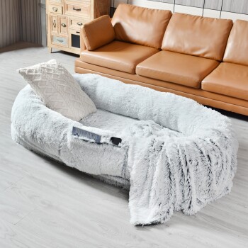 Gemütliches hellgraues Haustierbett mit plüschiger Textur, begleitet von einem dekorativen Kissen, in einem modernen Wohnzimmer platziert.