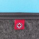 Nahaufnahme eines grauen Haustierbettes mit einem Reißverschluss, mit einem roten Etikett mit einem Ahornblatt-Logo an der Seite, vor einem hellblauen Hintergrund.