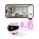 Ein pinker Haustierkamera-Roboter mit einem herzförmigen LED-Display steht neben seiner Ladestation, während ein Smartphone eine Live-Ansicht eines modernen Wohnzimmers zeigt.