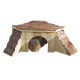 Ein hölzernes Kaninchenhaus mit einem mit Rinde bedeckten Dach und seitlichen Eingängen, mit einem braunen Kaninchen, das aus der vorderen Öffnung schaut.