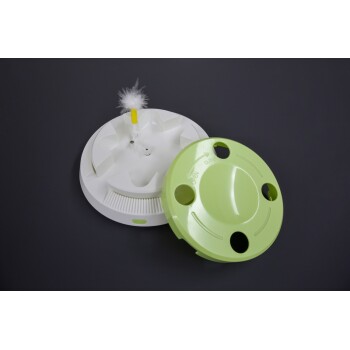 Interaktives Katzenspielzeug mit weißer Basis, Federköder und grünem Deckel mit den Beschriftungen "OPEN" und "CLOSE" sowie Löchern.