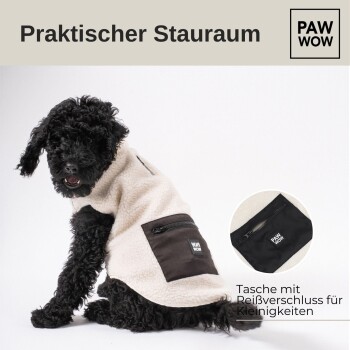 Ein schwarzer Hund trägt eine beigen Fleecejacke mit einer braunen Reißverschlusstasche, mit dem Text "PAW WOW" auf der Tasche.