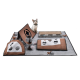 Eine verspielte Katze sitzt neben einer Vielzahl interaktiver Haustierspielzeuge, darunter Kratzpads und gemütliche Verstecke in Braun und Grau.