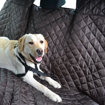 Ein hellfarbener Hund liegt auf einem braunen, gesteppten Autositzbezug, gesichert mit einem schwarzen Geschirr.