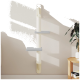 Wandmontierter Katzenbaum mit drei grauen Plattformen auf einem weißen Pfosten, vor einer hellen Wand, mit einer Pflanze und Möbeln in der Nähe.