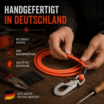 Person hält eine orangefarbene Leine, neben ihr sitzt ein schwarz-weißer Hund an einem Teich umgeben von Grün.