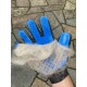 Eine Hand, die einen blauen Haustierpflegehandschuh trägt, hält einen Klumpen Tierhaare, mit einer strukturierten Steinoberfläche im Hintergrund.