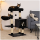 Ein schwarzer Katzenbaum mit drei Ebenen hält zwei schildpattfarbene Katzen oben und eine schwarz-weiße Katze, die aus einem würfelförmigen Versteck späht.