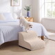 Kleiner weißer Hund tritt auf beige Haustiertreppe, um auf ein Bett in einem hellen Schlafzimmer mit blauer Bettwäsche, Holz-Nachttisch und Vase zu klettern.