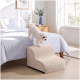 Kleiner weißer Hund tritt auf beige Haustiertreppe, um auf ein Bett in einem hellen Schlafzimmer mit blauer Bettwäsche, Holz-Nachttisch und Vase zu klettern.