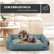 Ein kleiner Hund ruht auf einem weichen blauen Bett in einem hellen Wohnzimmer, mit dem Text: "ZUM EINKUSCHELN" und "schafft ein gemütliches Ambiente."
