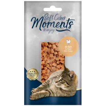 Emballage de friandises pour animaux Soft Cubes Moments présentant un chat tigré se prélassant à côté d'une fenêtre transparente montrant des cubes de poulet en dés, moelleux.