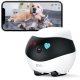 Eine weiße und schwarze Haustierkamera mit einem Herzsymbol wird vor einem Smartphone gezeigt, das einen Golden Retriever und eine graue Katze auf einem Bett anzeigt.