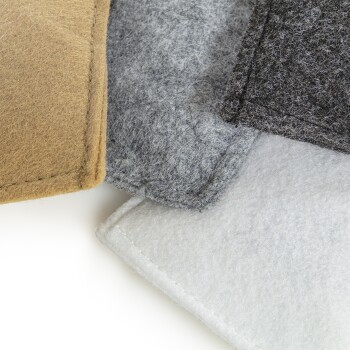 Eine Nahaufnahme von vier Filz-Haustiermatten in verschiedenen Farben: braun, grau, schwarz und weiß, auf einem weißen Hintergrund gestapelt.