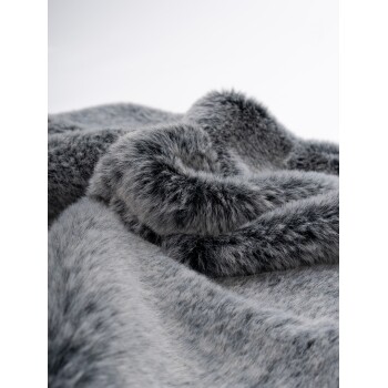 Weiche graue Kunstfell-Decke mit plüschiger Textur, elegant drapiert und eingerollt.