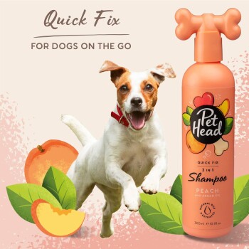 Ein verspielter weißer Hund springt fröhlich neben einer Flasche Pet Head 2-in-1 Pfirsichshampoo mit Arganöl, beschriftet mit "Quick Fix für Hunde unterwegs."