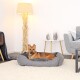 Ein entspannter Hund, der in einem gemütlichen grauen Haustierbett auf einem weichen Teppich liegt, mit einer stilvollen Lampe und modernen Möbeln in einem hellen Wohnzimmer.