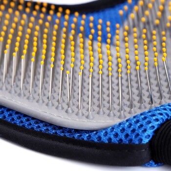 Nahaufnahme einer Haustierpflegebürste mit Metallborsten und gelben Spitzen auf einem grauen Grund, vor einem blauen Netz-Hintergrund.