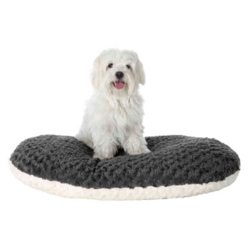 Ein kleiner, flauschiger weißer Hund sitzt glücklich auf einem plüschigen, ovalen Hundebett mit einem dunkelgrauen Oberteil und einem cremefarbenen Boden.