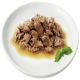 Une assiette blanche contenant une portion de viande humide et effilochée dans une sauce, garnie d'une branche de menthe fraîche.
