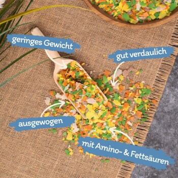 Bunte Fischfutterflocken in einer Holzschale auf einer Holzoberfläche, mit einem Aufkleber, der "Beste Qualität - 10 Jahre" auf Deutsch besagt.