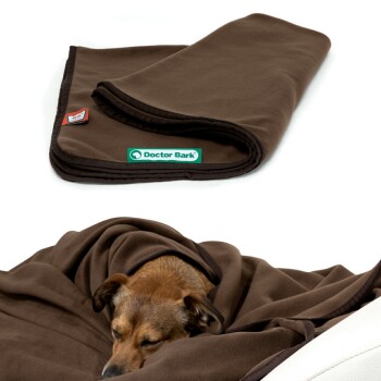 Ein schlafender Hund in einer weichen braunen Fleece-Decke, mit dem Text oben, der sagt "EXTRA WEICH & KUSCHELIG" und seinen Komfort und seine Qualität hervorhebt.