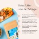 Bild von Haustierfutterverpackungen mit frischen Zutaten wie Hähnchen, Früchten und Samen. Der Text hebt Qualität und Zubereitungsmethoden hervor.