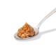 Eine Nahaufnahme eines silbernen Löffels, der einen Klecks cremiger, brauner Haustierleckerei-Paste hält, vor einem weißen Hintergrund.