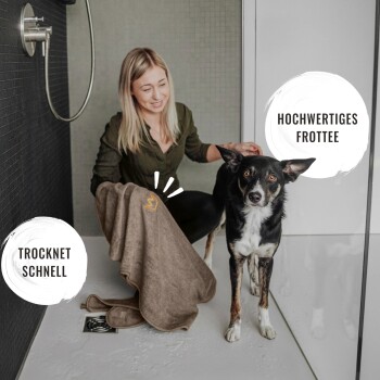 Frau trocknet einen schwarz-weißen Hund in der Dusche mit braunem Handtuch; Text lautet "TROCKNET SCHNELL" und "HOCHWERTIGES FROTTEE".