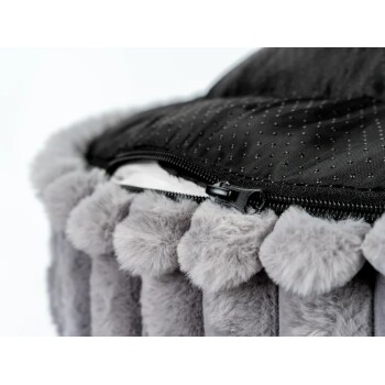 Nahaufnahme eines grauen Plüsch-Haustierbetts mit schwarzem Reißverschluss und gepunktetem rutschfestem Bodenstoff.