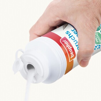 Eine Hand gießt weißes Pulver aus einem Beaphar-Haustierergänzungsmittelbehälter, der mit bunten Grafiken und dem Wort 'Probiotikum' beschriftet ist.