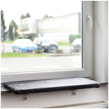 Eine graue Katzenfensterbank, die auf einer Fensterbank montiert ist, mit Blick auf geparkte Autos und ein Gebäude draußen.