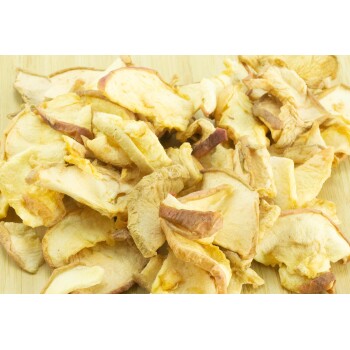 Getrocknete Apfelscheiben, die auf einer Holzoberfläche gestapelt sind und ihre goldenen und hellbraunen Farben zeigen, ideal für Hundeleckerlis.