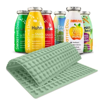 Eine Sammlung von bunten Hundesmoothie-Flaschen mit der Aufschrift "SmoothieDog" in verschiedenen Geschmacksrichtungen, neben einer hellgelben Silikonmatte mit knochenförmigen Formen.