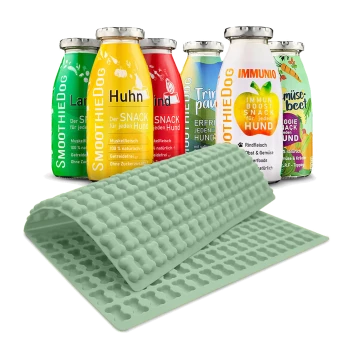 Eine Sammlung von bunten Hundesmoothie-Flaschen mit der Aufschrift "SmoothieDog" in verschiedenen Geschmacksrichtungen, neben einer hellgelben Silikonmatte mit knochenförmigen Formen.