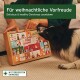 Eine Frau sitzt auf dem Boden neben einem Hund und hält eine Box mit der Aufschrift '24 WEIHNACHTEN', während ein Adventskalender für Haustiere ausgestellt ist.