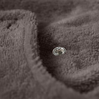 Nahaufnahme einer weichen, braunen Haustierdecke mit einem sichtbaren Metall-Druckknopf, die ihre plüschige Textur zeigt.