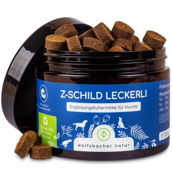 Ein Glas mit Hundeleckerlis, beschriftet mit "Z-SCHILD LECKERLI" in einem blauen und grünen Design, das braune, würfelförmige Snacks enthält.