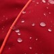 Nahaufnahme eines roten wasserdichten Stoffes mit Wassertropfen, die auf der Oberfläche perlen und seine wasserabweisenden Eigenschaften zeigen.
