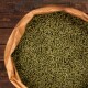 Eine Nahaufnahme einer großen Tasche, die mit grünen Haustierfutterpellets gefüllt ist und auf einer Holzoberfläche ruht.