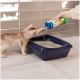 Eine hellfarbige Katze greift nach einer blauen Katzentoilette, während eine Hand Katzenstreu aus einem grünen und blauen Behälter schüttet.