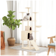 Zwei Katzen spielen auf einem hohen beigen Katzenbaum mit mehreren Ebenen und Verstecken, in einem hellen Raum mit einer Pflanze und gemütlicher Dekoration.