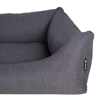 Graues Haustierbett mit einem plüschigen, gepolsterten Design und erhöhten Seiten, mit einem kleinen schwarzen Etikett mit dem Markennamen.