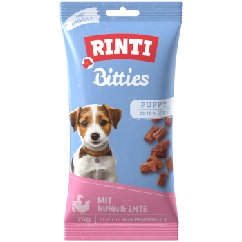 Przysmaki dla szczeniąt RINTI Bitties, opakowanie niebiesko-różowe, napis 'PUPPY EXTRA SOFT', 'MIT HUHN & ENTE', 75 g, obraz psa i kawałki.