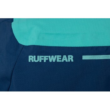Nahaufnahme einer blauen und türkisfarbenen Hundejacke mit dem Markennamen "RUFFWEAR" deutlich sichtbar.