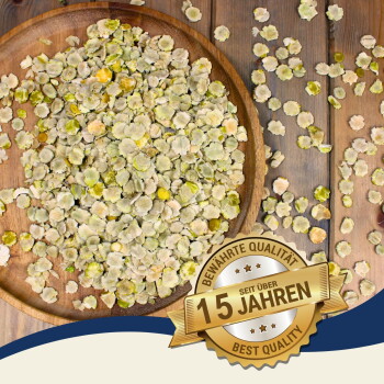 Getrocknete grüne und gelbe Haustierfutterflocken, die auf einem Holzbrett verteilt sind, mit einem goldenen Abzeichen, das "Beste Qualität - 15 Jahre" auf Deutsch angibt.