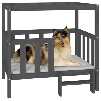 Ein flauschiger Collie, der auf einem grauen Holzhaustierbett mit einer weichen Matratze liegt, das mit einem Sicherheitsgeländer und einer kleinen Stufe ausgestattet ist.