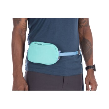 Ein Mann trägt ein blaues Hemd und schwarze Shorts, zeigt einen hellblauen Ruffwear-Hüftbeutel, der um seine Taille gesichert ist.