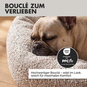 Ein schlafender Französischer Bulldogge auf einem gemütlichen, donutförmigen Hundebett mit dem Text "süße Träume" und Details: "Boucle-Stoff," "Donut Form," "Anti Rutsch."