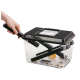 Eine Hand, die einen schwarzen Griff an einem transparenten Insektenhabitat mit einem schwarzen Deckel hält, das lebende Grillen und eine gelbe Futterschale enthält.